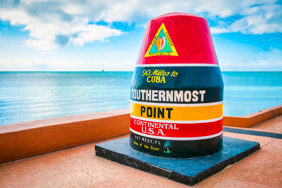 An empty scenic view of the colorful concrete buoy featuring the municipal seal of Key West marking the southernmost point of the continental USA in Florida. 